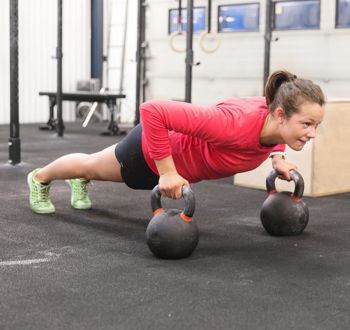 Young hard working women trains push ups at crossfit gym center.